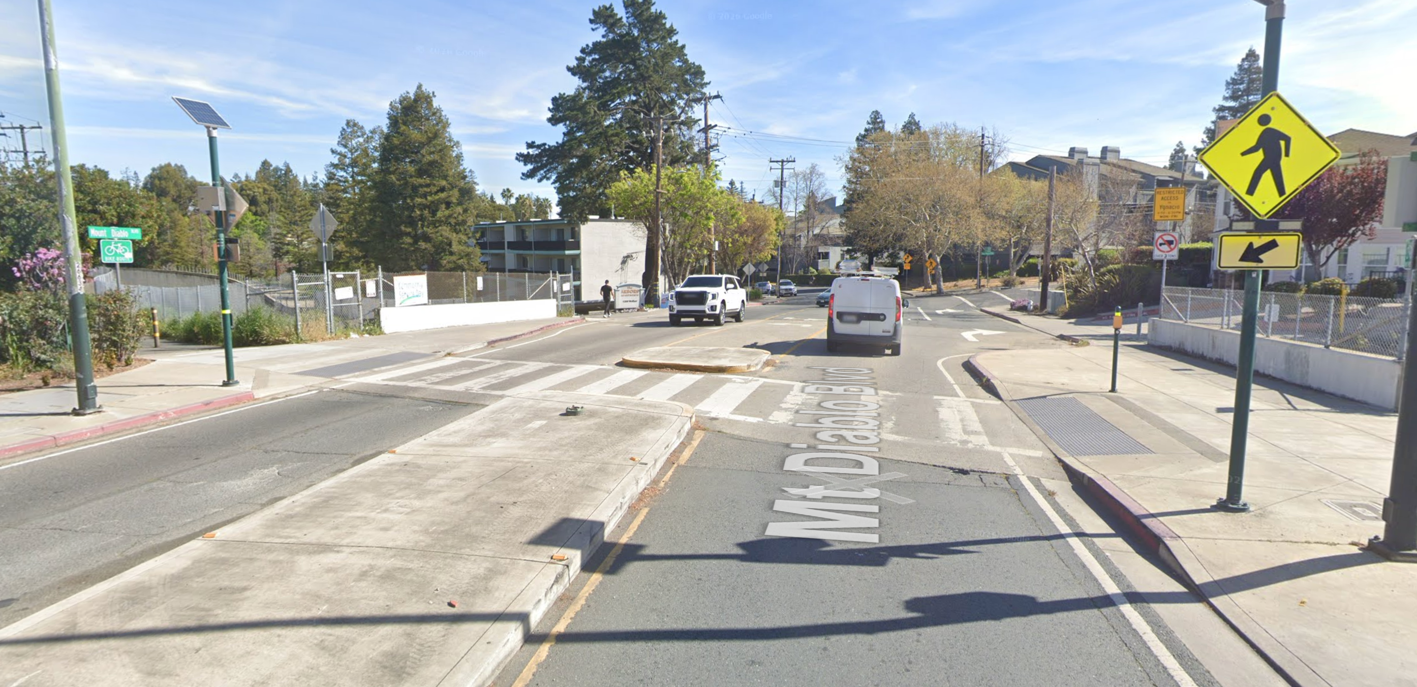 Mt. Diablo Boulevard at the Iron Horse Trail crossing, showing a small concrete center median with no pedestrian crossing sign on it